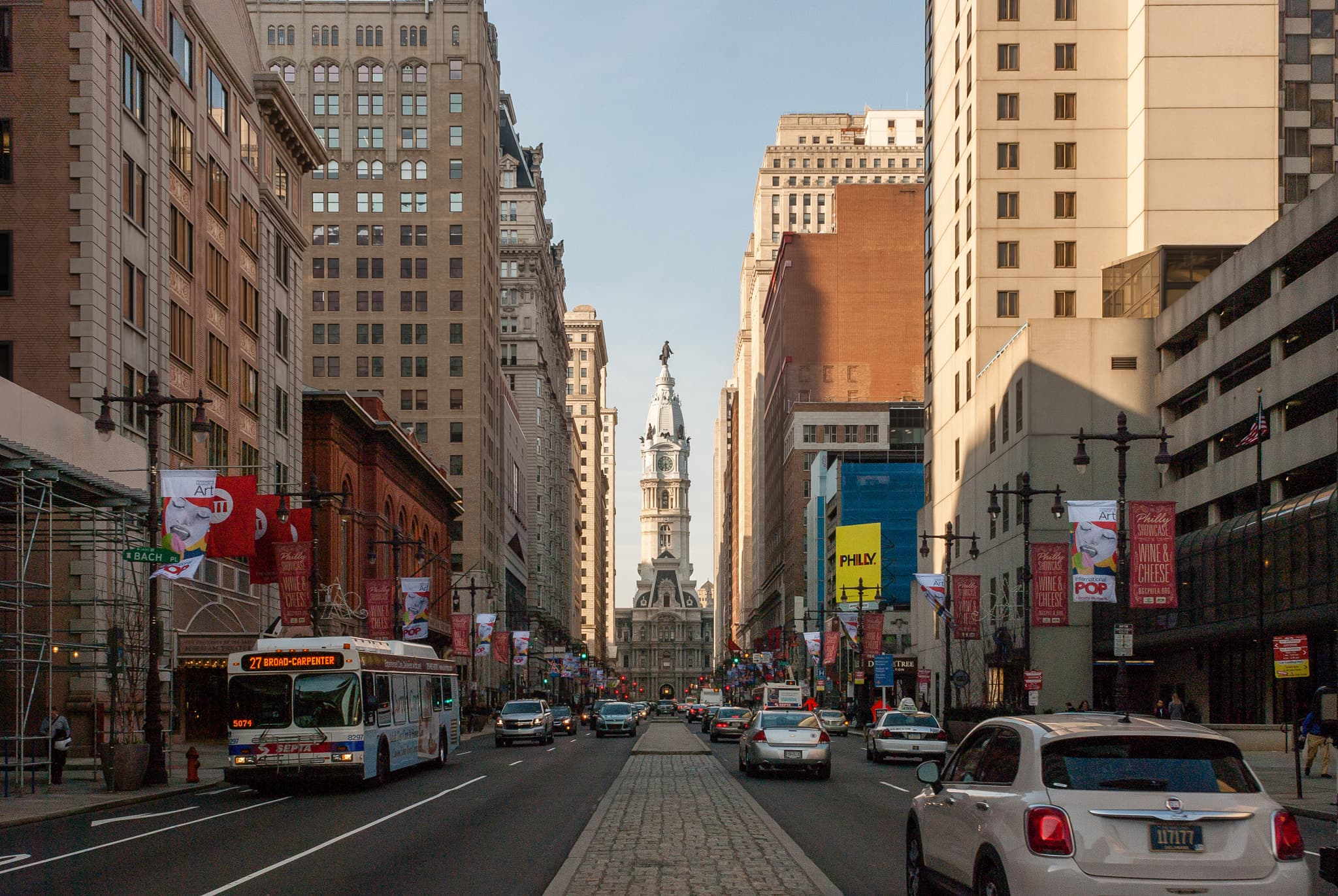 Philadelphia City Hall seen along Broad Street, with buildings and everyday traffic in the foreground.
